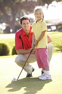 Father Teaching Daughter To Play Golf On Putting On Green