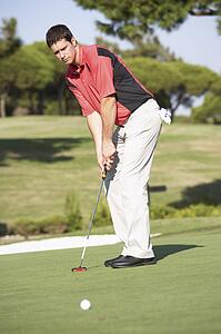 Male Golfer On Golf Course Putting On Green