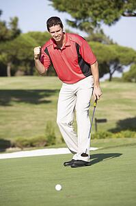 Male Golfer On Golf Course Putting On Green