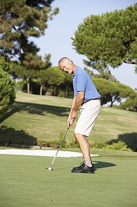 Senior Male Golfer On Golf Course Putting On Green