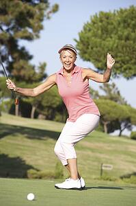 Senior Female Golfer On Golf Course Lining Up Putt On Green