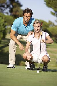 Couple Golfing On Golf Course Lining Up Putt On Green