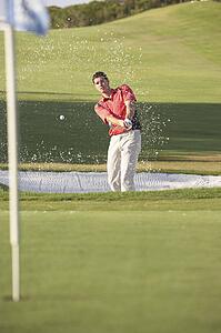 Male Golfer Playing Bunker Shot On Golf Course