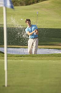 Male Golfer Playing Bunker Shot On Golf Course
