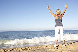 Senior Woman In Fitness Clothing Stretching On Beach