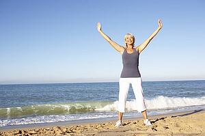 Senior Woman In Fitness Clothing Stretching On Beach