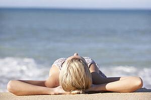 Young Woman Sunbathing On Beach 