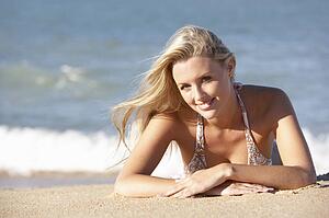 Young Woman Sunbathing On Beach 