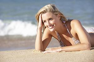 Young Woman Sunbathing On Beach 