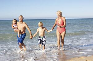 Grandparents With Grandchildren Enjoying Beach Holiday Together