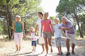 A family, with parents, children and grandparents, walk through park