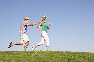 Senior couple running though field