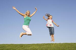 Senior woman with granddaughter jumping in air
