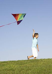 Young boy runs with kite through field