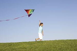 Young boy runs with kite through field
