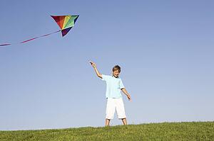 Young boy poses with kite in a field