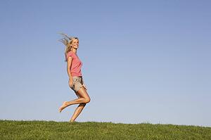 Young woman running through field