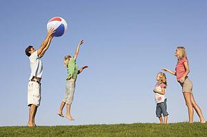 Young family, parents with children, playing in a field