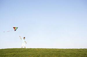 Young boy flying kite in a field