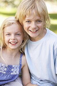 Brother and sister pose in a park