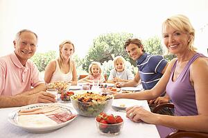 Extended family, parents, grandparents and children, eating outdoors
