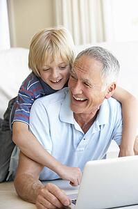 Senior man with young boy using laptop computer