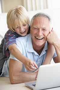 Senior man with young boy using laptop computer