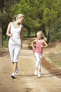Mother and daughter running in park