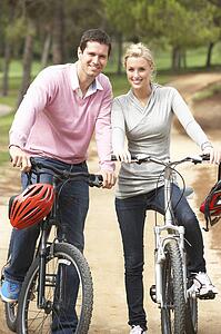 Couple riding bicycle in park