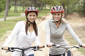 Two Female friends riding bikes in park