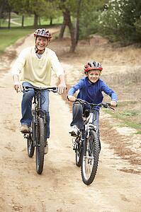 Grandfather and grandson riding bicycle in park