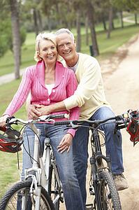 Senior couple riding bicycle in park