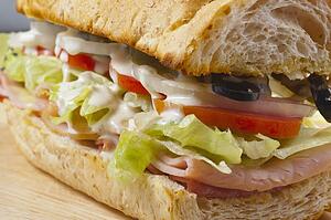 A Sandwich With Meat, Vegetables And Olives