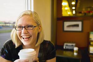 a young woman smiling with coffee at a cafe