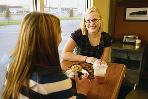 two women talking at a table in a cafe