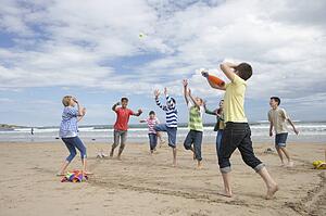 Teenagers playing baseball on beach