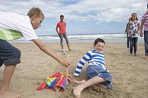 Teenagers playing baseball on beach