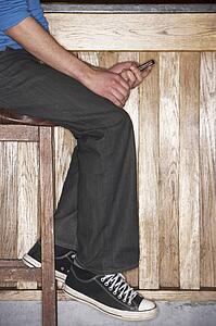 Young man sitting at bar with mobile phone