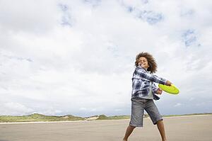 Boy playing frisbee on beach
