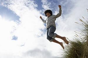 Boy jumping over dune