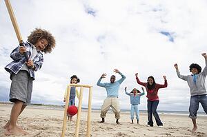 Family playing cricket on beach