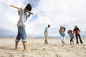 Family playing cricket on beach