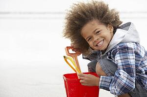 Happy boy at beach with bucket and spade