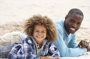 Father and son laying on beach