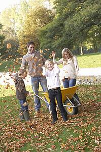 Family throwing autumn leaves into the air in garden