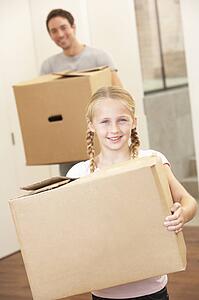 Girl with young man on moving day carrying cardboard box