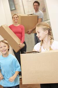 Family happy on moving day carrying cardboard boxes