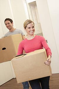 Young couple on moving day carrying cardboard boxes