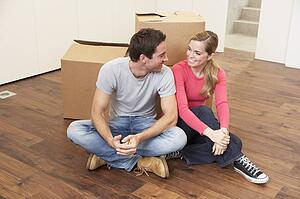 Young couple on moving day sitting with cardboard boxes