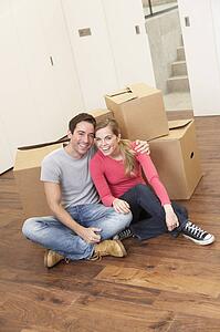 Young couple on moving day sitting with cardboard boxes